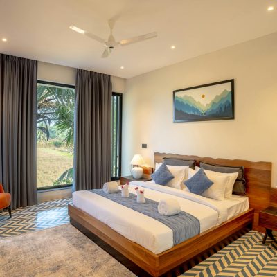 Elegant modern villa bedroom with scenic garden view in Saligao, Goa.