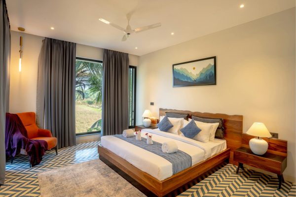 Elegant modern villa bedroom with scenic garden view in Saligao, Goa.