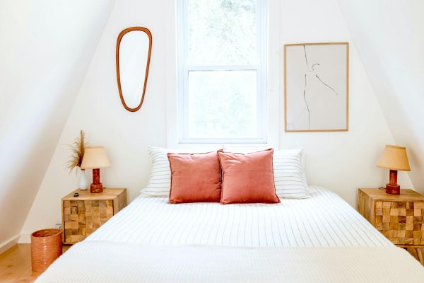 Inviting minimalist bedroom with modern decor, warm lighting, and soft pillows in Catskill, NY.